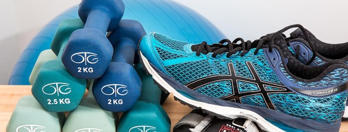 A running shoe rests on a stack of dumbbell weights.