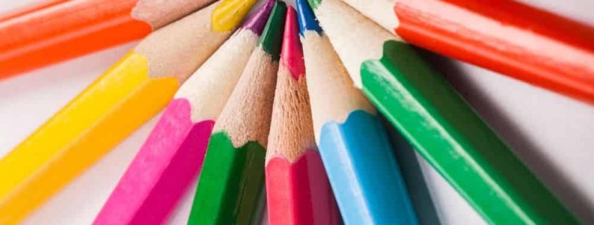 Colourful pencil crayons are arranged with all the points together, looking like a sun.