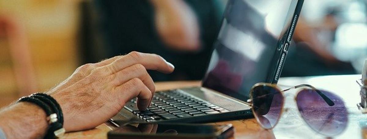 Adult male hands type on a laptop computer.