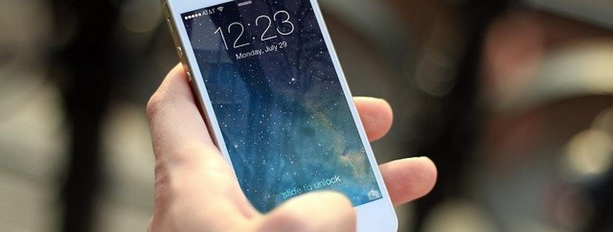A hand holds a white iPhone 6.