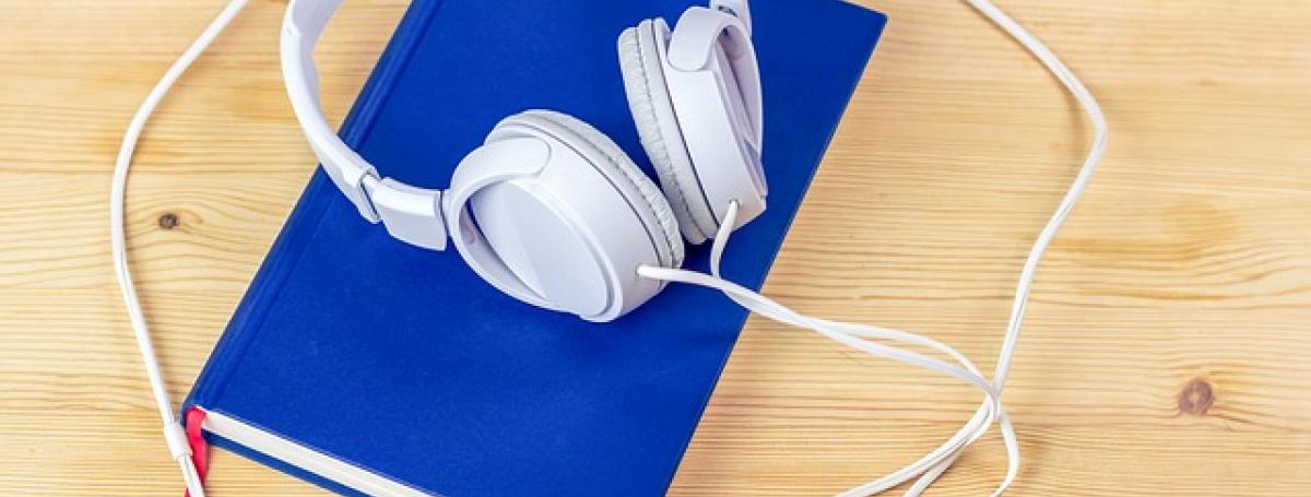 A blue book with headphones resting on top.