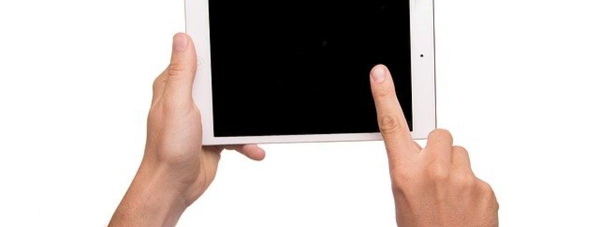 Two hands type on an iPad screen.