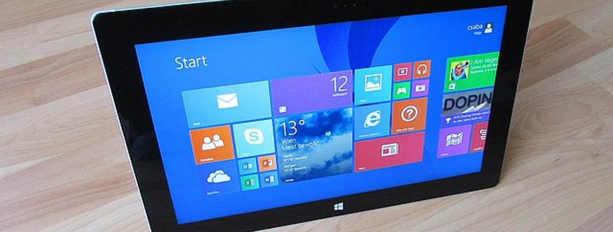 A microsoft tablet sits on a table top.
