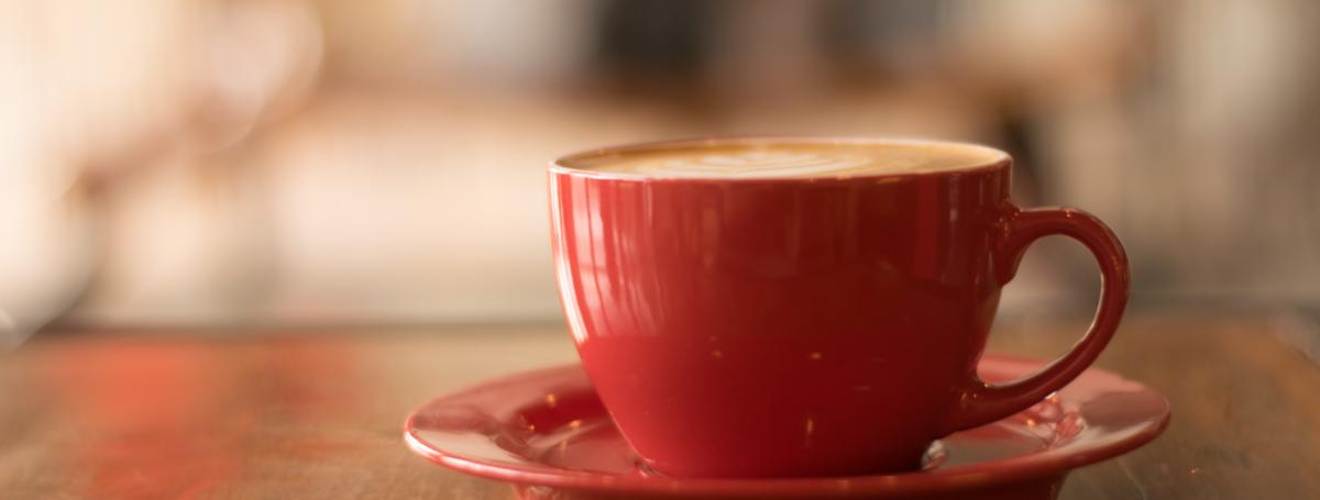 Red tea cup on a saucer on a wooden table.