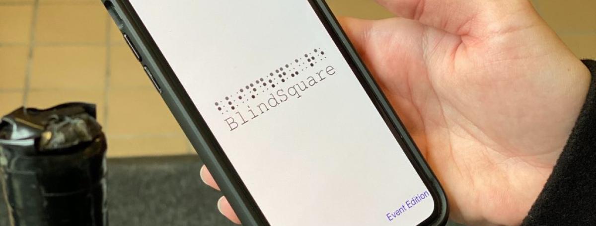 A smartphone screen displays the BlindSquare app.