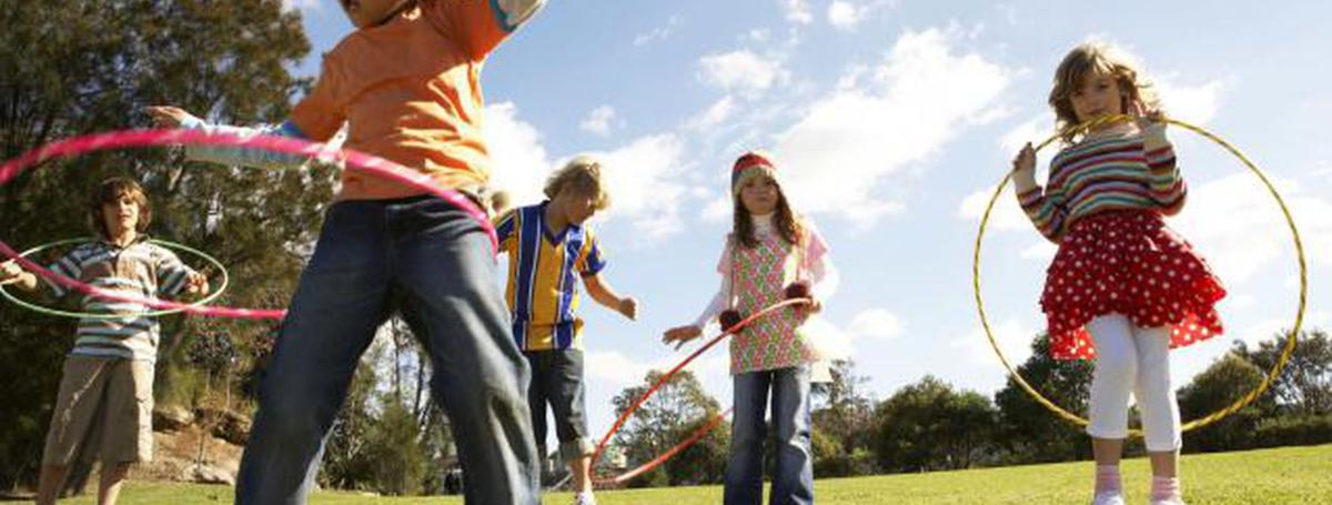 Five children are outdoors with hula hoops.