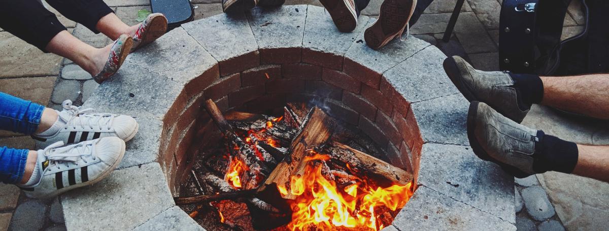 Bird's eye view of a campfire pit with people resting their feet on the stones.