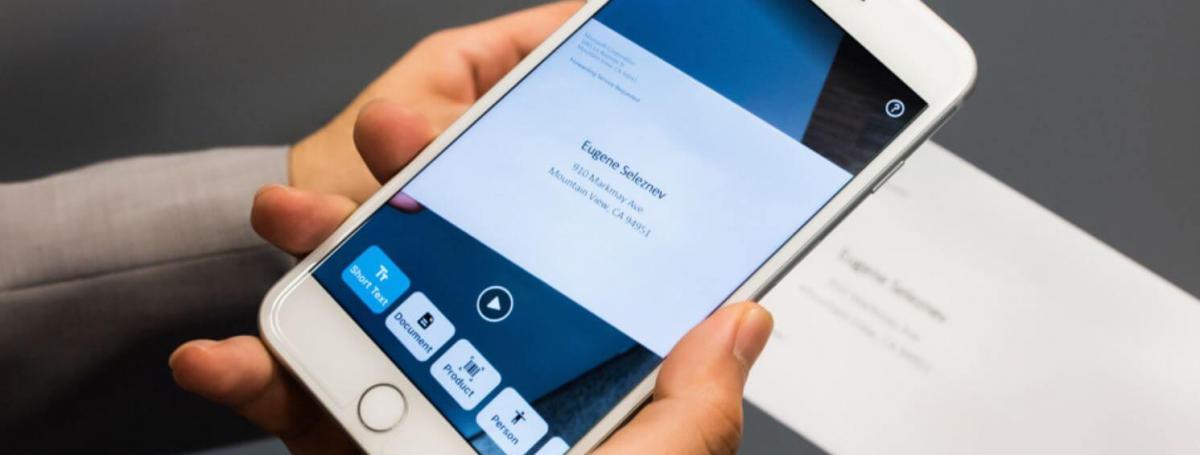 An iPhone has the Seeing AI app open and scanning an envelope. 
