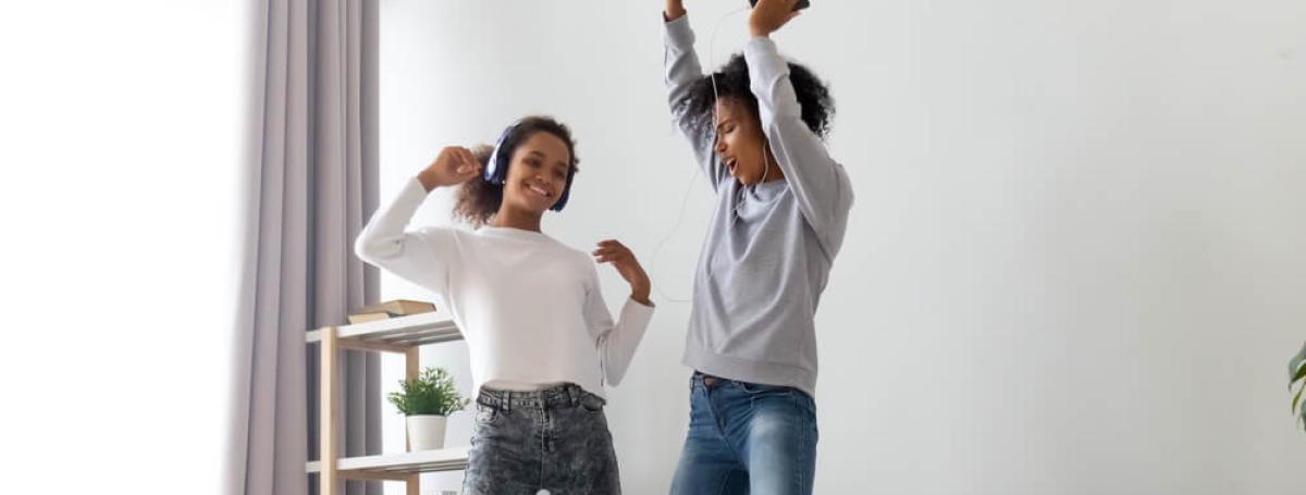 Two young women signing and dancing on a bed