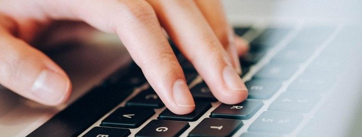 Hands typing on a black laptop keyboard.