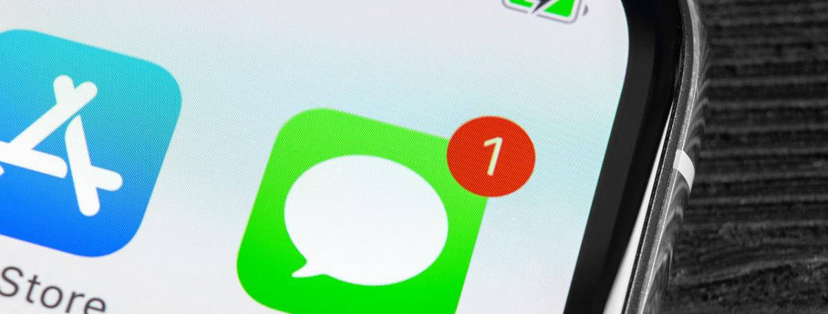 Gros plan du coin d'un téléphone. On voit l'application Messages (une belle dans un carré vert) avec un petit 1 dans un cercle rouge pour indiquer 1 nouveau message, à côté de l'application Apple Store.