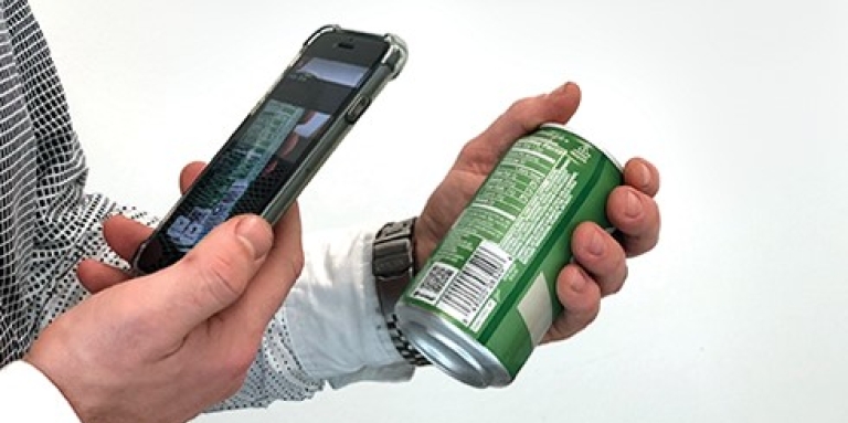 Une main tient un téléphone cellulaire devant le code-barre d'une canette