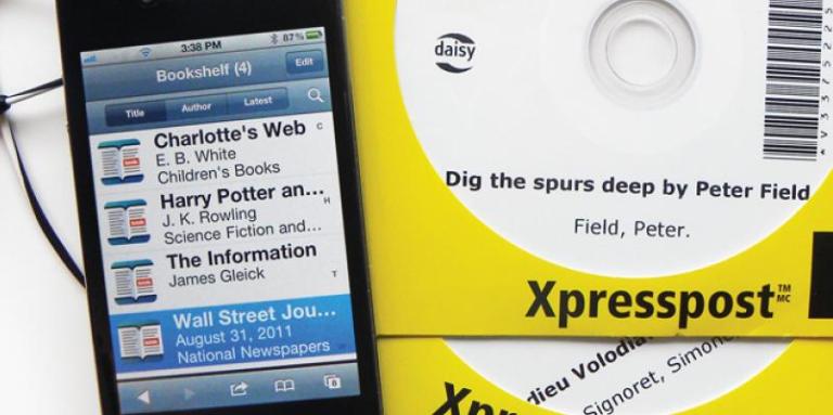 Photo of a Victor Stream displaying a reader’s bookshelf, next to DAISY books on CD.
