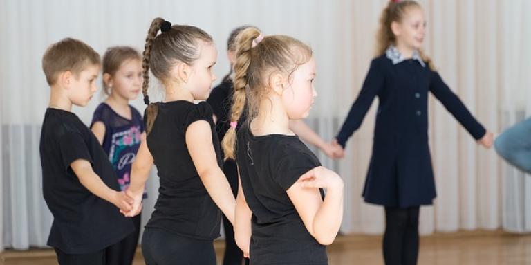 A group of children hold hands and stand in a circle.