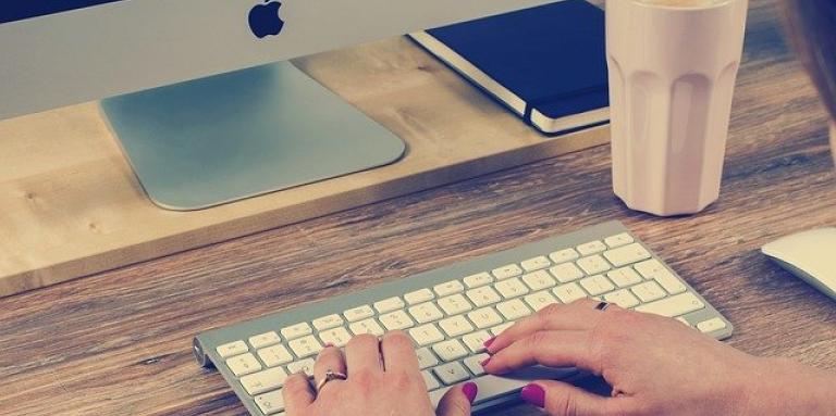A woman's hands type on a computer keyboard.