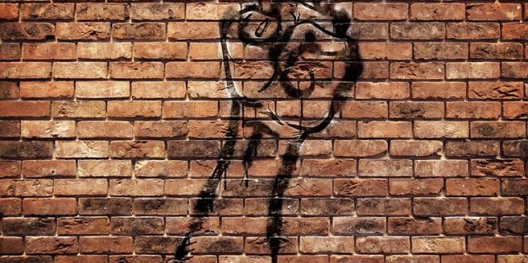 Artistic graffiti of a fist on a brick wall. Made with black spray paint.