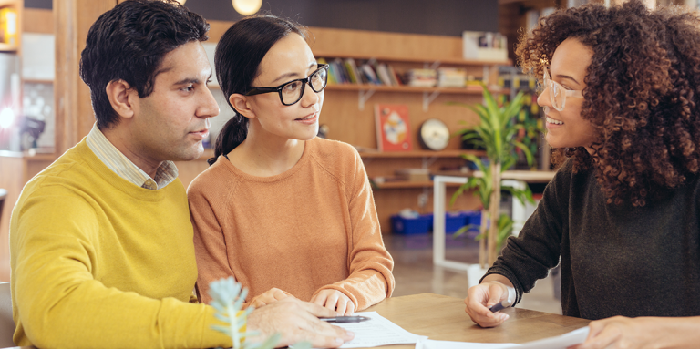 Two parents meet with a teacher at a conference.