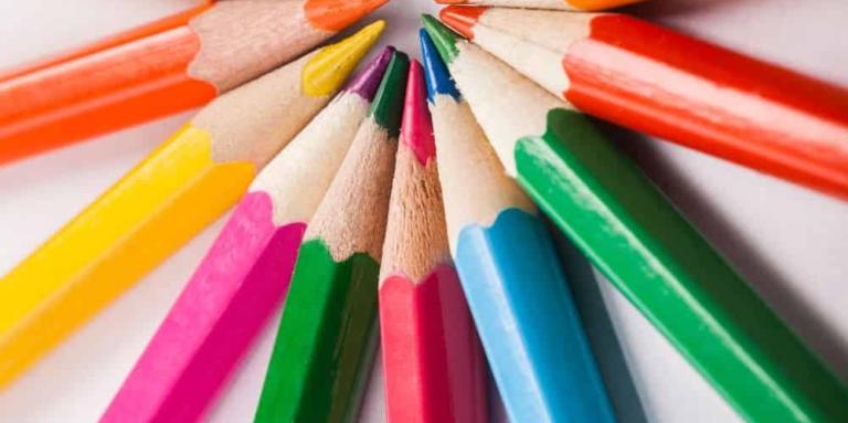 Colourful pencil crayons are arranged with all the points together, looking like a sun.