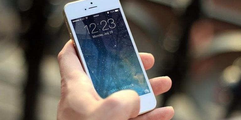 A hand holds a white iPhone 6.