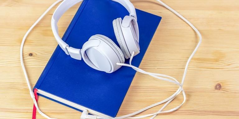 A blue book with headphones resting on top.