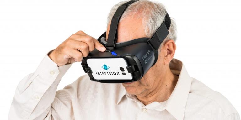 An older man wears an IrisVision headset.