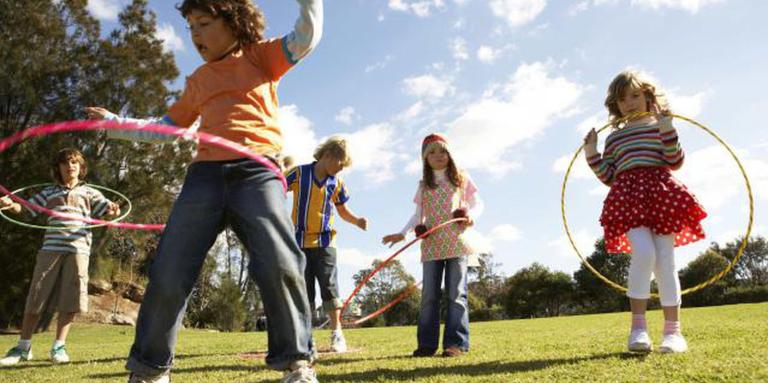 Five children are outdoors with hula hoops.