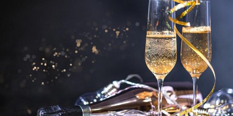 Two champagne flutes sit on a confetti covered table.
