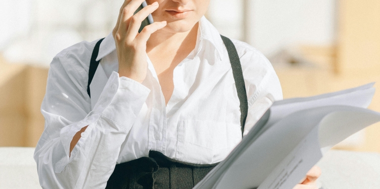 Une jeune femme en tenue professionnelle au téléphone.