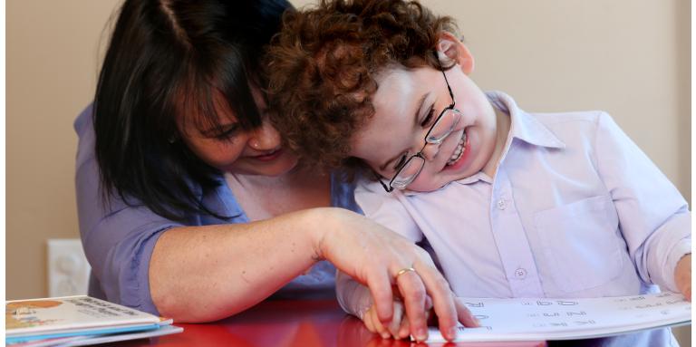mother and son reading a book in braille