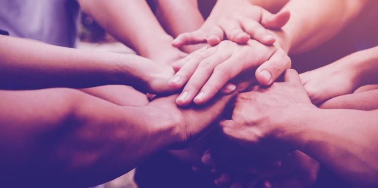 Hands stacked on top of each other in a circle.