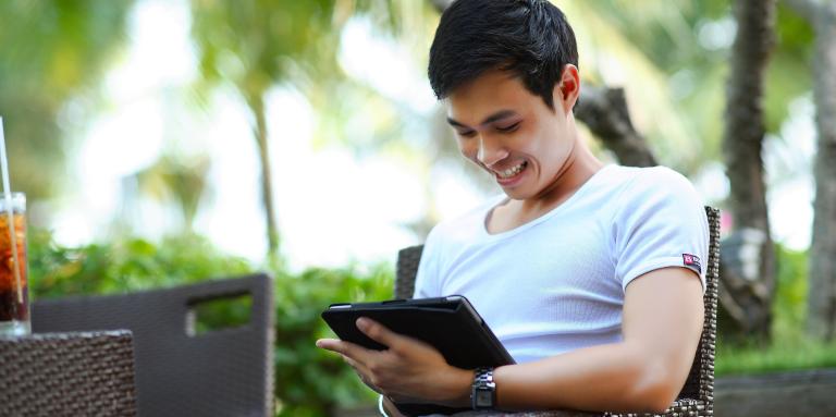 Un homme sourit à l'écran de son iPad