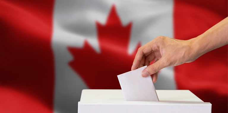 A hand dropping a ballot into a box; the Canadian flag in the background.