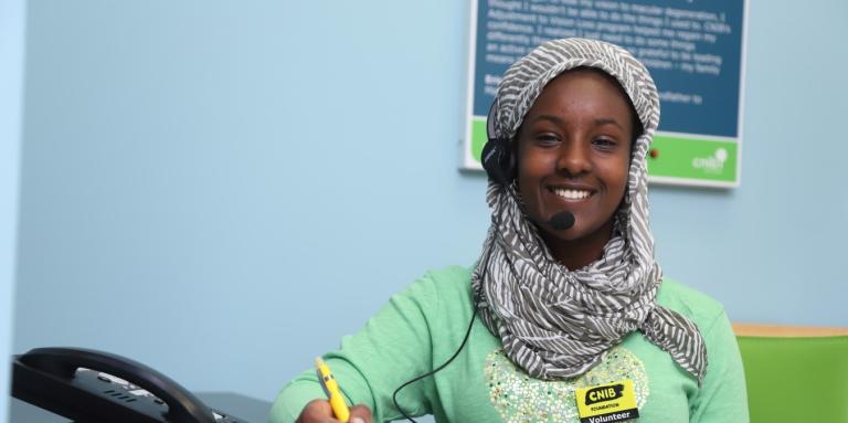 One of CNIB's volunteers smiling while talking on the phone