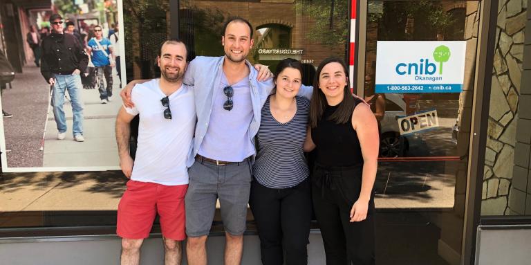 Russell Enns, Brian Malcolm, Noemi Stroda and Sierra Sanger, smiling for the camera in front of a CNIB office.