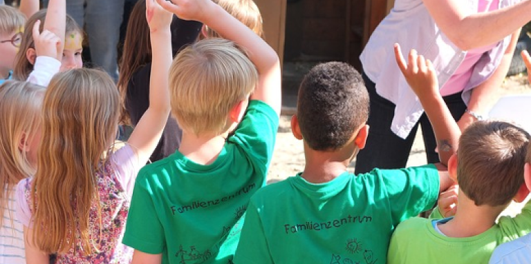  Un groupe de jeunes enfants lève les mains en l'air pour répondre à une question