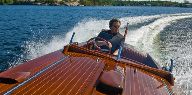 Man in wooden boat on Lake Muskoka.