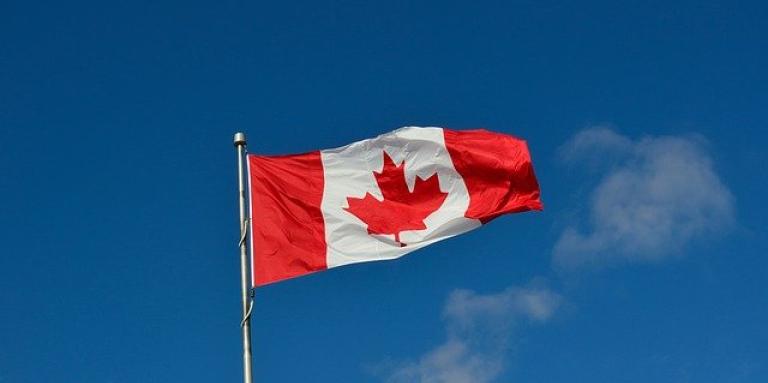 Un drapeau canadien flotte dans un ciel bleu et clair.