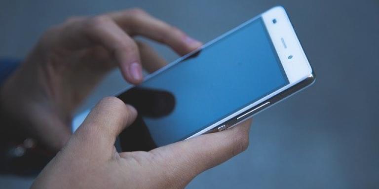 Two hands hold an android phone. The smartphone screen is black.