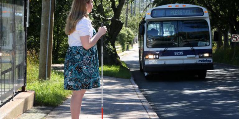 Woman with a white cane waiting for the bus