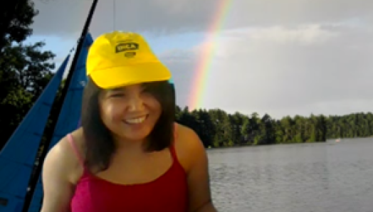 Najla porte une casquette jaune souriant à côté d'un lac