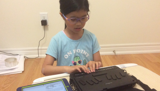 Janna using an iPad and BailleNote Touch to read a book from Bookshare