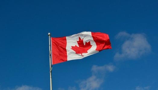 A Canadian flag waves in a clear, blue sky.