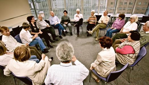 A large group of 17 people gather in a support group. They are seated in a circle.