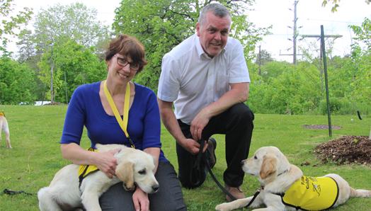 Karen and Andrew with two puppies in yellow vests.