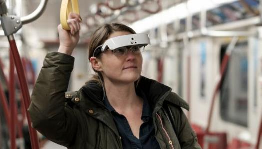 A woman wearing eSight glasses stands in a subway car.