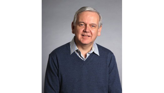 Photo of Jim Maher sitting in front of a grey background.