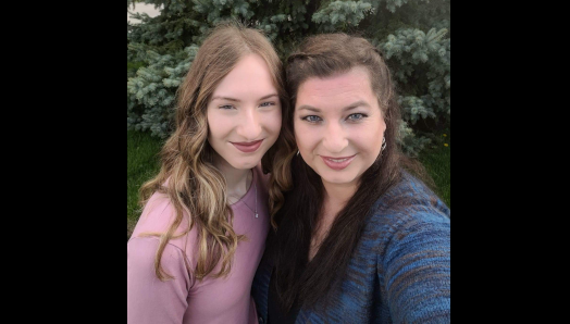 Emma (à gauche) et Michelle (à droite) sourient et posent pour une photo devant un bel arbre vert.