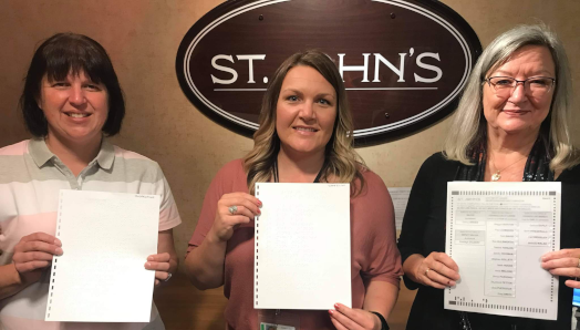 Kim Hart, INCA, Trisha Rose, coordonnatrice des élections de la ville de St John, et Debbie Ryan, INCA, tenant le premier bulletin de vote en braille utilisé lors des élections municipales de 2021.