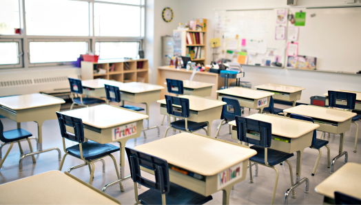 Une salle de classe d'école primaire avec des rangées de bureaux vides.